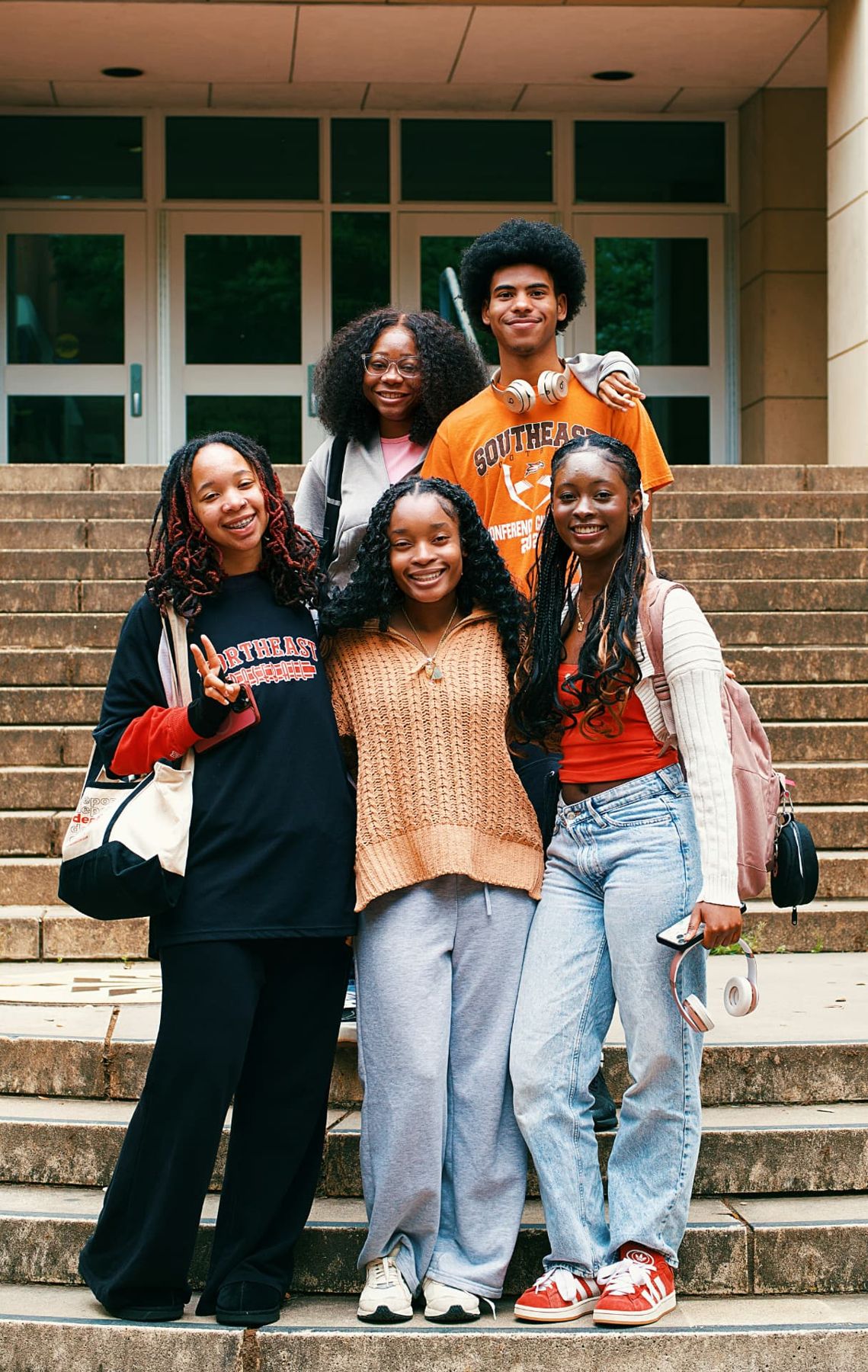 Five young people sitting together on outdoor steps